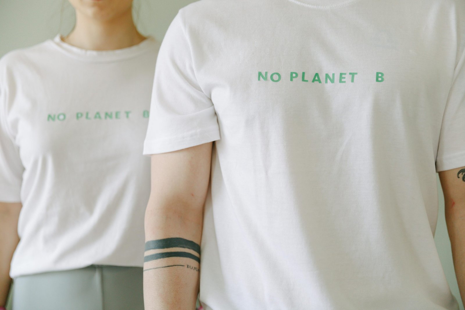 Home Close-up of two people wearing white 'No Planet B' T-shirts, promoting environmental awareness.