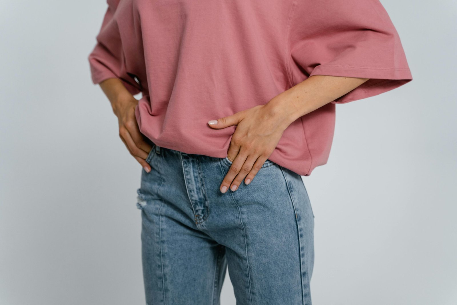 Home Stylish outfit featuring a pink oversized t-shirt and blue denim jeans in a studio setting.