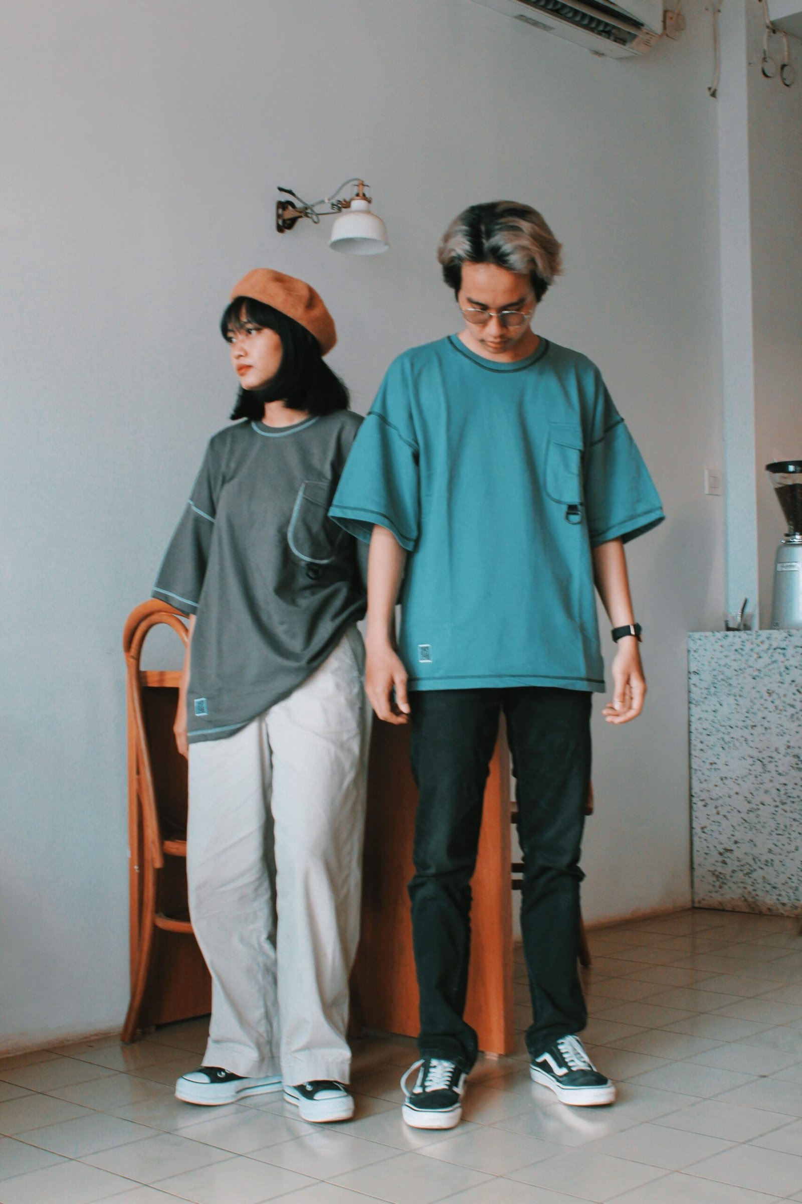 Two teenagers in casual fashion pose indoors, showcasing modern style and expression.